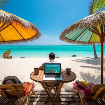 Freelancer using laptop on a beach with umbrellas - Image 1