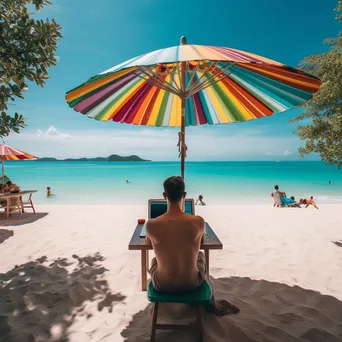 Freelancer using laptop on a beach with umbrellas - Image 3