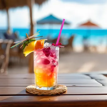 Close-up of a tropical drink on a seaside table with blurred beach scenery in the background. - Image 3