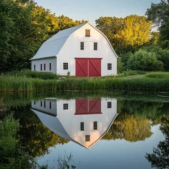 Classic white barn reflecting in pond at sunrise - Image 2