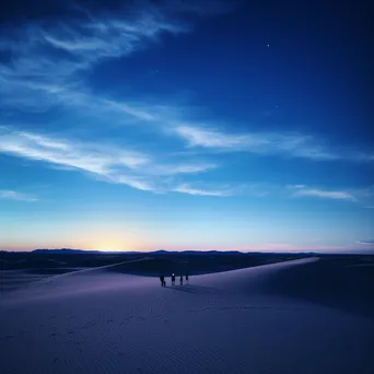 Silhouettes of people wandering through sand dunes at twilight - Image 1