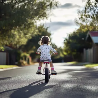 Child learning to ride their first bicycle on a quiet street - Image 3