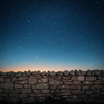 Dry stone wall set against a starry sky at twilight. - Image 1