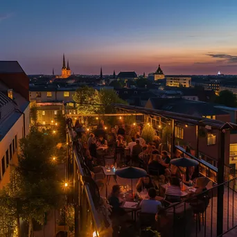 A rooftop terrace filled with people during a summer evening party - Image 1