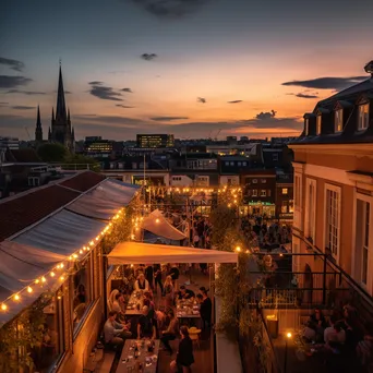 A rooftop terrace filled with people during a summer evening party - Image 2