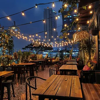 Elegant cafe terrace with string lights and city views at night - Image 1