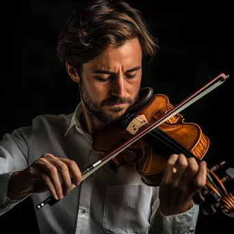 Violinist playing softly under ambient lighting during a performance. - Image 1