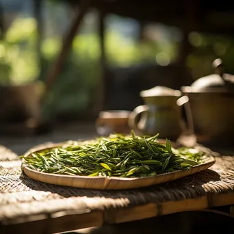 Fresh tea leaves drying on a bamboo mat - Image 3