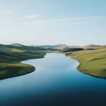 Aerial view of a tranquil blue lake surrounded by green hills. - Image 1