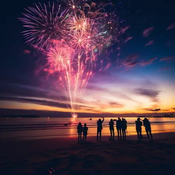 Fireworks lighting up a beach with people silhouetted watching the New Year