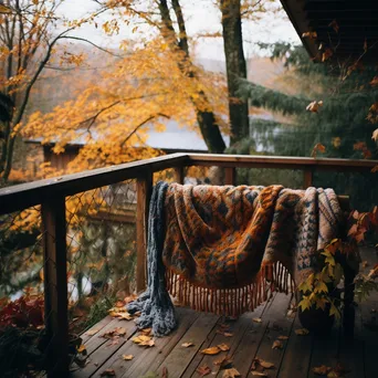 Wooden deck covered in autumn leaves with a sweater draped over the railing - Image 2