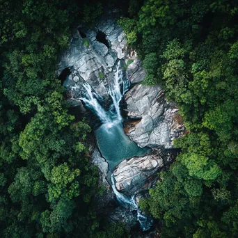 Aerial view of a cascading mountain waterfall and forest - Image 1