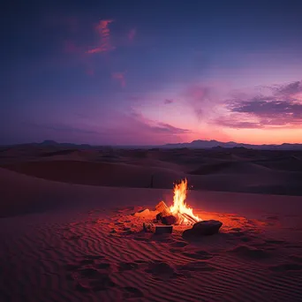 Campfire glowing against sand dunes at twilight - Image 1