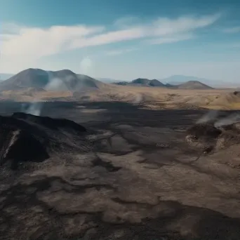 Aerial view of a volcanic landscape with a smoking crater and lava fields - Image 2