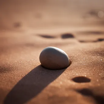 Smooth stone placed in soft sand - Image 2